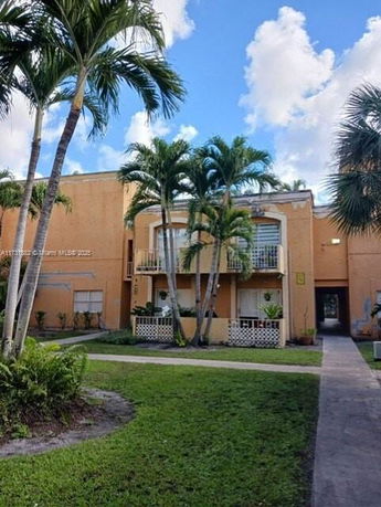 Front view of a multi-story building with balconies and palm trees.