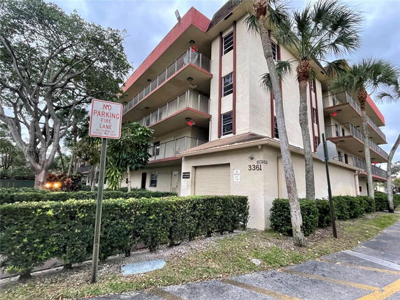 Front view of a multi-story building with balconies and a no parking fire lane sign.