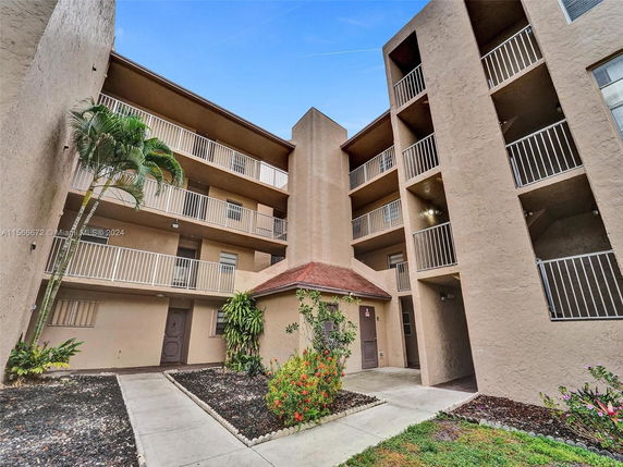 Front view of a multi-story residential building with balconies and outdoor walkway.