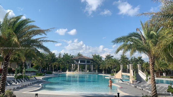 Outdoor swimming pool area with lounge chairs and palm trees.
