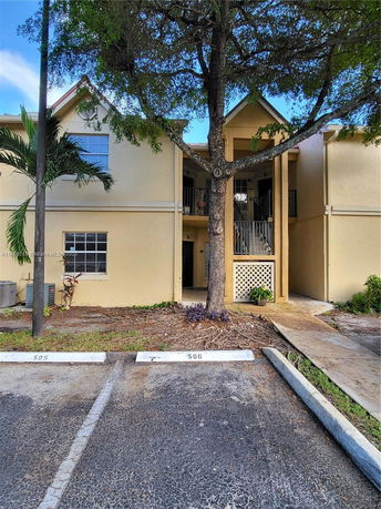 Front view of a two-story residential building with a tree in front.
