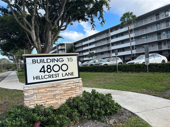 Front view of a multi-story residential building with a sign that reads 'Building 15, 4800 Hillcrest Lane'.