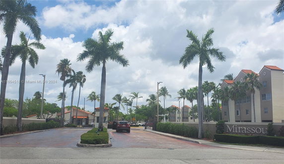 Front view of residential buildings with palm trees lining the entrance.
