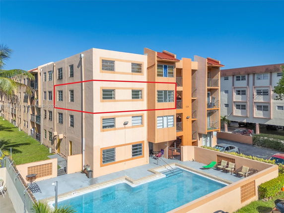 Front view of a multi-story apartment building with a swimming pool.