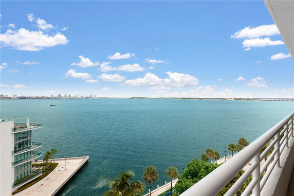 Panoramic view of the ocean from a building, showing a blue sky and distant city skyline.