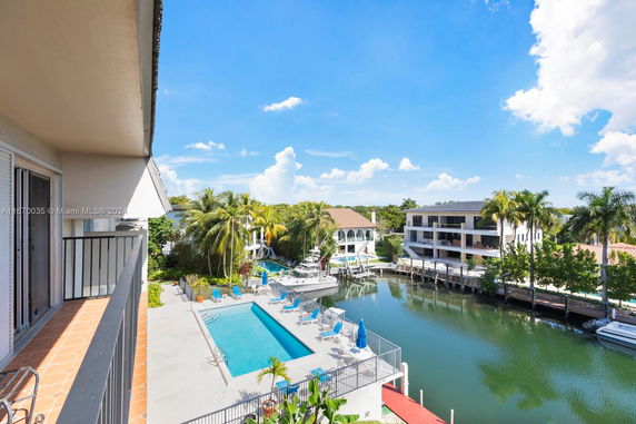 View from a balcony overlooking a swimming pool, canal, and nearby residential buildings.