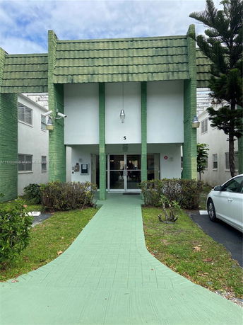 Front view of a building with a green and white exterior and a covered entrance.