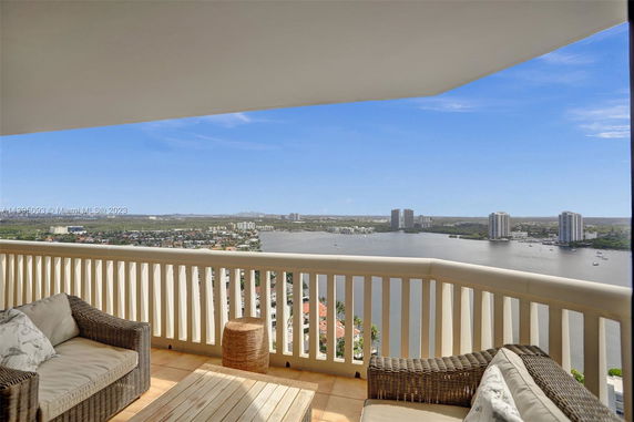 Panoramic view from a high-rise balcony overlooking a waterfront cityscape.