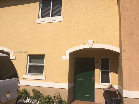 Front view of a two-story house with a green door and yellow exterior.