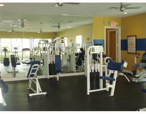 Indoor gym area with exercise machines and mirrored walls.