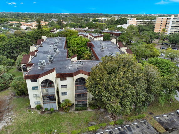 Aerial view of a multi-story building with a flat rooftop featuring multiple air conditioning units.