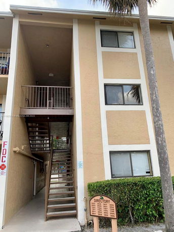 Front view of a multi-story building with external stairs and directory sign.