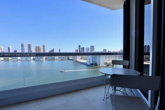 Panoramic view from a balcony overlooking a city skyline and water body.