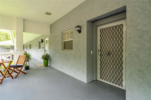 Front view of a building entrance with a security door and outdoor seating.