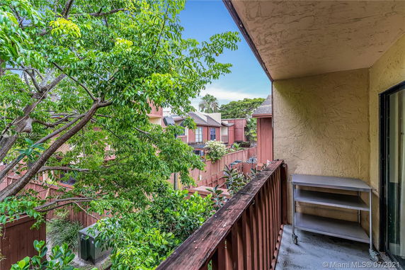 View from a balcony overlooking neighboring houses and greenery.