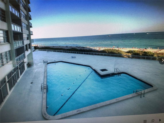 Outdoor swimming pool next to a building with a view of the ocean.