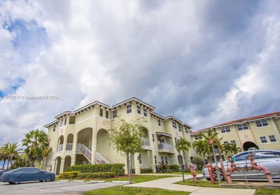 Front view of a multi-story residential building with balconies and arched entries.