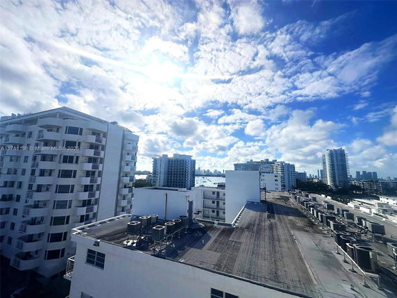 Rooftop view with air conditioning units and distant cityscape.