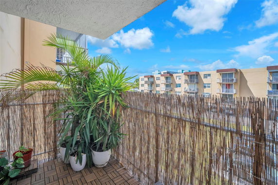 View from a balcony with potted plants and nearby multi-story buildings.