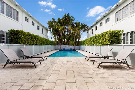 Outdoor swimming pool area with lounge chairs and surrounding greenery.