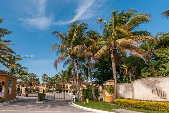 Main entrance of a condominium complex with palm trees and gated entry.
