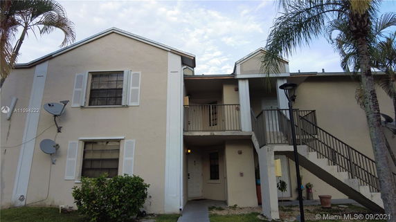 Front view of a two-story apartment building with external staircases and satellite dishes.