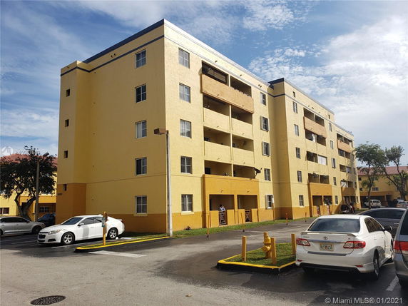 Front view of a multi-story yellow apartment building with balconies.