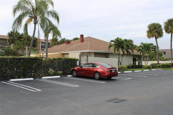 Outdoor parking area with marked spaces and a red car.
