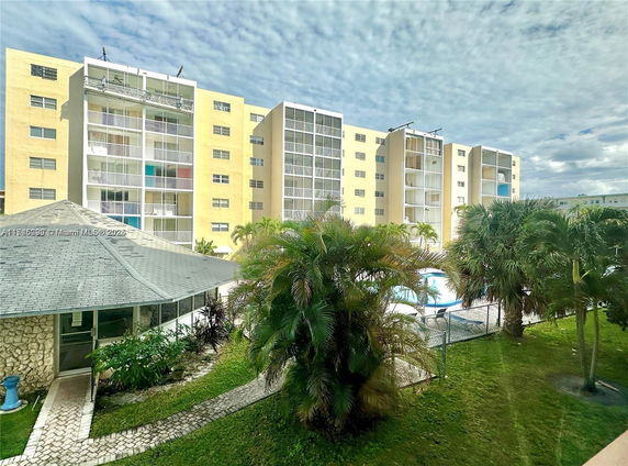 View of multi-story apartment buildings with balconies and surrounding greenery.