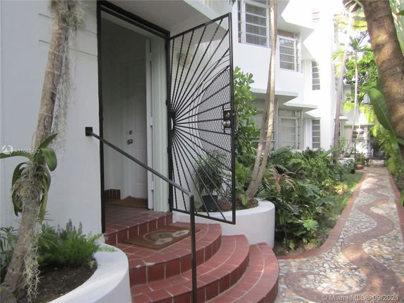 Entrance view of a building with a decorative metal gate and red brick steps.