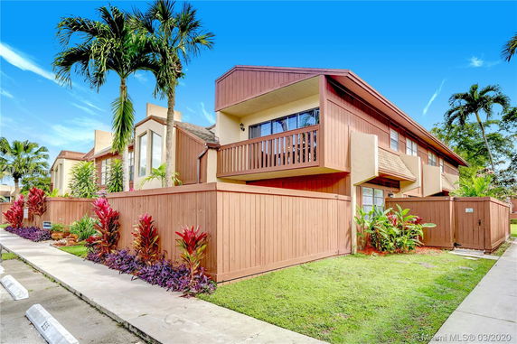 Front view of a two-story building with wooden paneling and a fenced area.