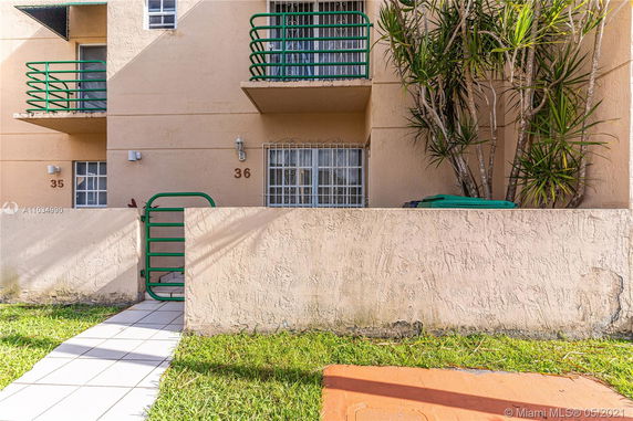Front view of a multi-story building with balconies and green railings.