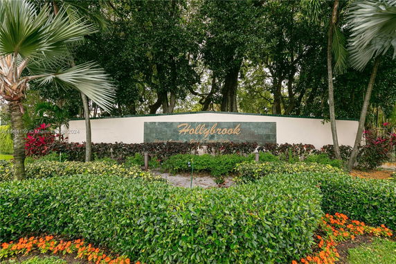 Entrance sign with landscaped greenery and trees.