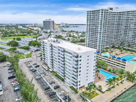 Aerial view of a housing complex with multiple tall buildings and adjacent swimming pool.