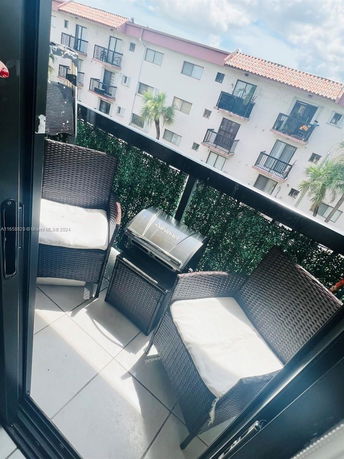 View from a balcony with chairs and a small grill looking out to adjacent residential buildings.