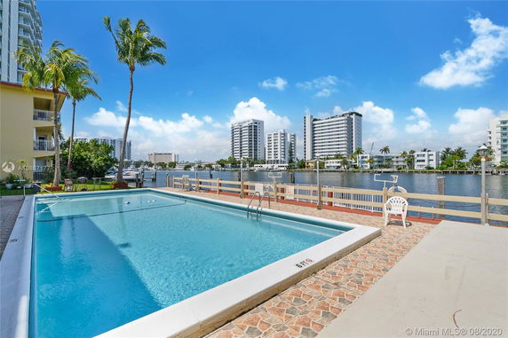 Outdoor swimming pool with a view of buildings across the water.