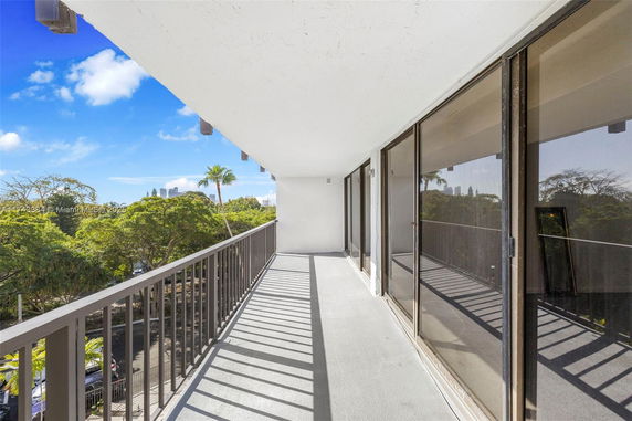 Balcony view with glass sliding doors and a view of trees and distant buildings.