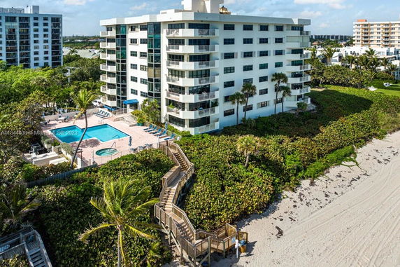 View of a multi-story beachfront building with balconies and adjacent swimming pool.