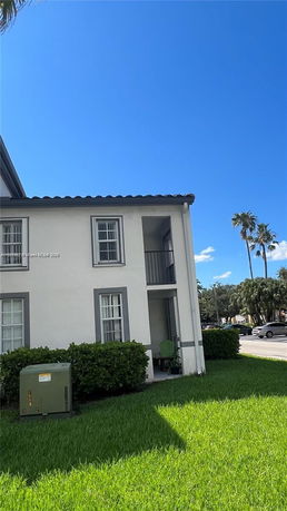 Front view of a two-story house with a small balcony and lawn.