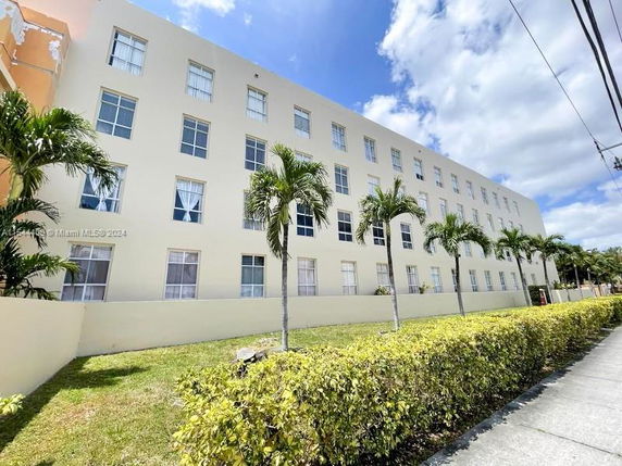 Front view of a multi-story building with multiple rectangular windows and a light color facade.