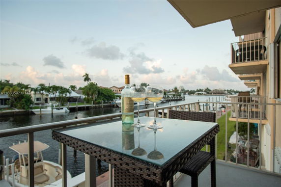 Balcony view overlooking a waterway with boats and houses in the background.