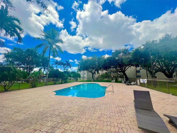 Outdoor swimming pool area with lounge chairs and surrounding trees.