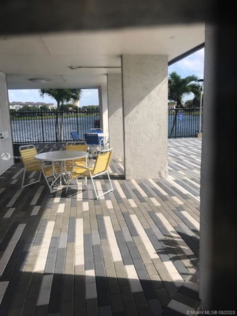 Covered outdoor patio area with seating and view of a lake.