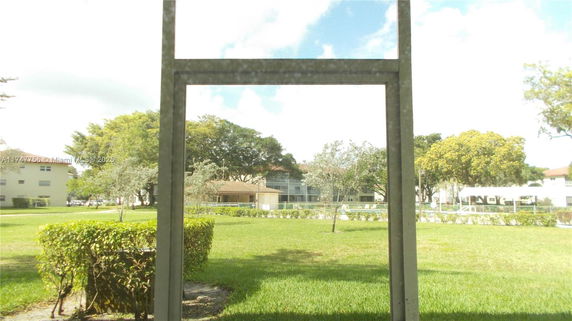 View from a building overlooking a grassy area with trees and other buildings in the distance.