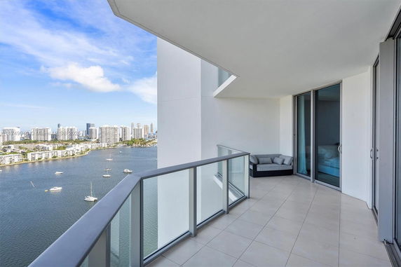 Balcony view with glass railing and a city skyline across the water.