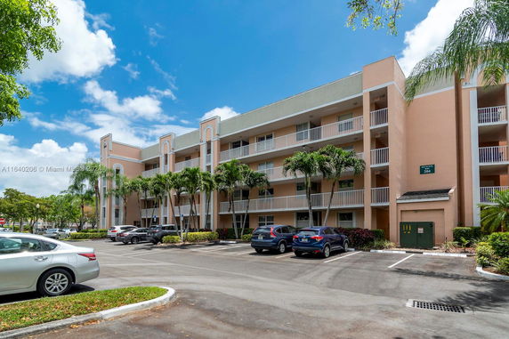 Front view of a multi-story apartment building with balconies and parking area.