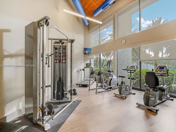 Interior view of a gym area with exercise equipment and large windows.