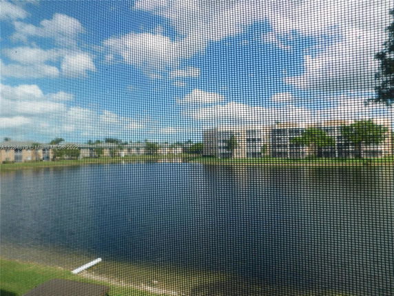 Buildings seen across a body of water through a mesh screen.