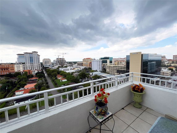 Panoramic view from a balcony overlooking a city skyline with various buildings and cloudy sky.