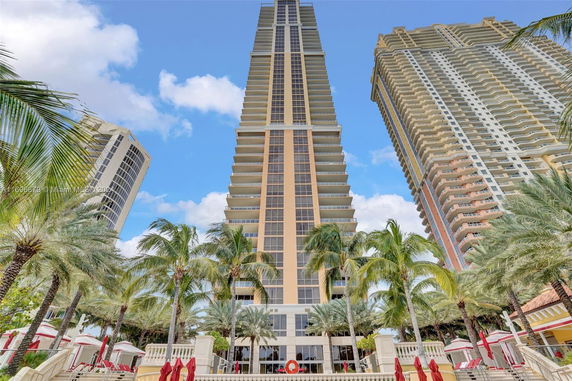 Front view of a tall, modern skyscraper with multiple floors and large balconies.